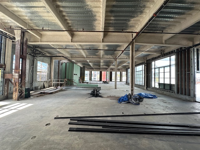 Interior of the Cine Latino building with exposed structural elements and construction materials on floor.