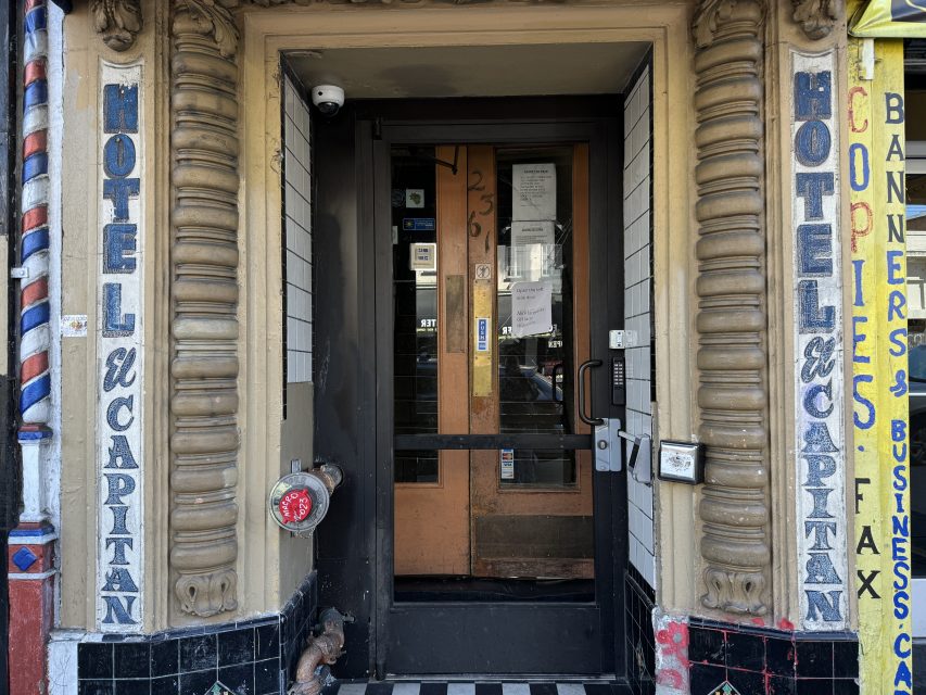 Facade of the entrance to hotel el capitan with surrounding business signs and a barber's pole.