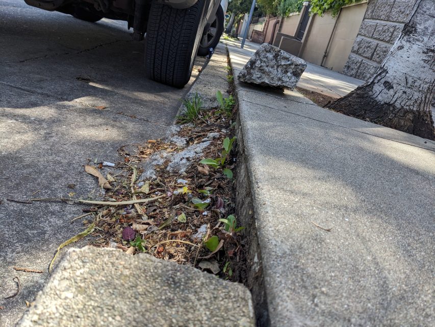 A piece of broken concrete on a pavement next to a parked vehicle.