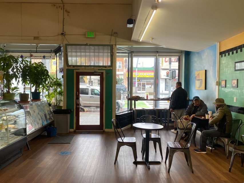 咖啡馆内部，顾客坐在桌边，透过前门可以看到街道。